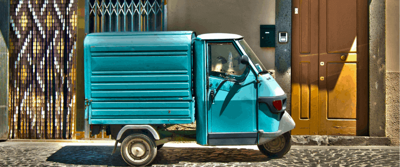Uma carrinha de entrega pequena e colorida em frente a uma porta