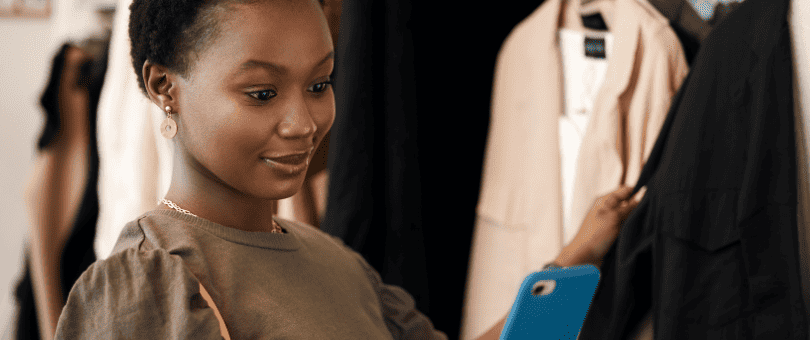 Uma mulher comprando roupas com um telefone celular para ilustrar a postagem no blog Signifyd April Pulse data - vendas no e-commerce