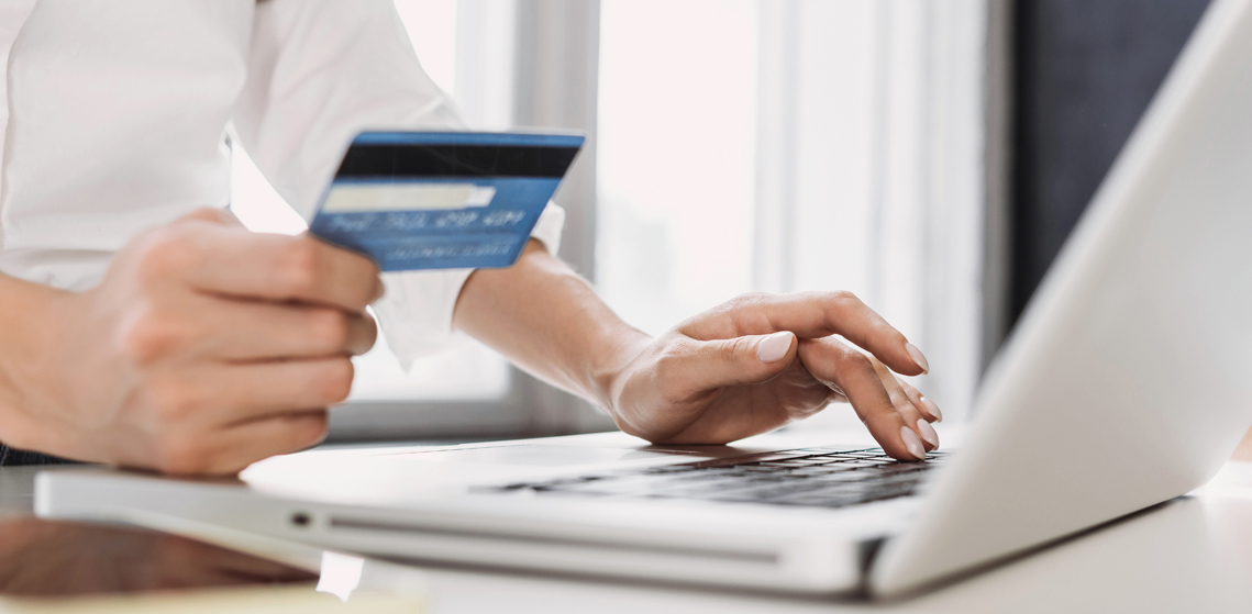 Taxa de aprovação de pedidos: o que afeta esse indicador? - Pessoa usando cartão de crédito em frente a um notebook,