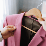 Mulher segurando um casaco rosa preso a um cabide.